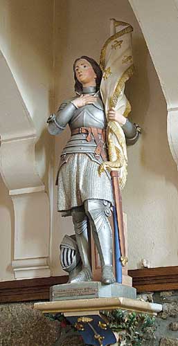 Painted Statue of Joan of Arc with banner inside a church in France