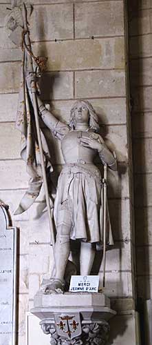 Picture of a statue of Joan of Arc with sign saying Merci Jeanne D Arc inside a church in France